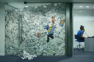 Image of man in office trapped by paperwork